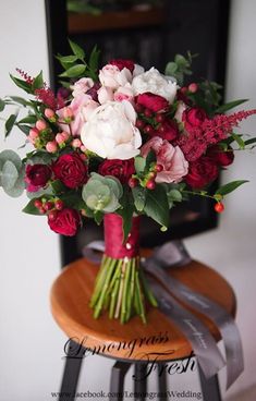 a bouquet of red and white flowers sitting on top of a wooden stool in front of a fireplace