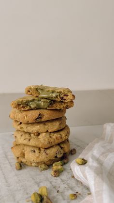 a stack of cookies with pistachios on top and one cookie in the middle