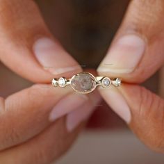 a close up of a person's hands holding a ring with a stone in it