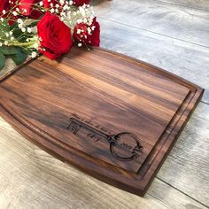 a wooden cutting board that has some flowers on it and red roses in the background