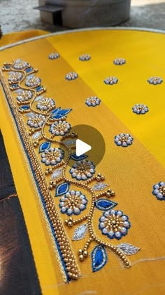 a yellow table cloth with blue and white designs on it, sitting on top of a wooden