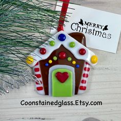 a gingerbread house ornament with candy on it and a merry christmas card next to it