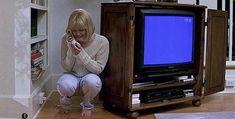 a woman sitting on the floor in front of a small tv with a blue screen