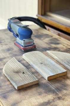 a cordless sanding machine and some wood planks on top of a table