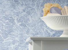 a white bowl filled with different types of items sitting on top of a dresser next to a blue wall