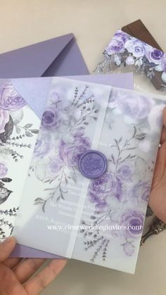 a person is holding some cards with flowers on them and purple ribbon around the edges