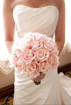 a bride holding a bouquet of pink roses