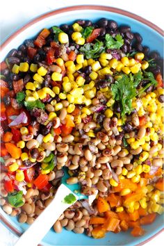 a bowl filled with beans, carrots and cilantro on top of a table