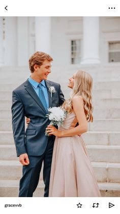 a man and woman standing next to each other in front of some steps with flowers