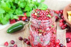 a glass jar filled with cranberry sauce next to some vegetables and chips on a table