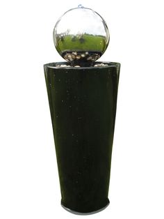 a glass ball is sitting on top of a black vase filled with rocks and gravel