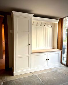 a large white cabinet with hooks on it's doors and drawers in a living room