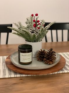 a candle and some pine cones on a wooden table with a place mat in front of it