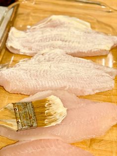 raw fish fillets are being prepared on a cutting board with a paintbrush in the foreground