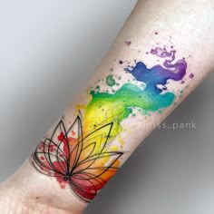 a colorful watercolor tattoo on the left arm and wrist with a flower in it