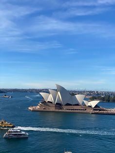 an aerial view of the sydney opera house and boats in the water, with blue skies above