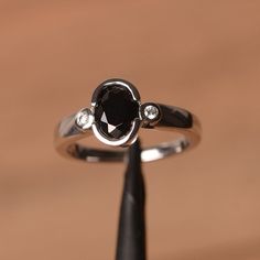 It is a natural black spinel ring. The main stone is 6 mm*8 mm oval cut.weight about 1.6 carats.The basic metal is sterling silver and plated with rhodium.To change the metal to a solid gold (white/rose) or platinum is also available, please ask for a quotation if you want.You can also go to my shop Home for more elegant rings: https://www.etsy.com/shop/godjewelry?ref=hdr_shop_menuMore black spinel rings:https://www.etsy.com/shop/godjewelry?ref=seller-platform-mcnav§ion_id=21680005Customization Black Spinel Ring, August Birthstone Ring, Swiss Blue Topaz Ring, Green Amethyst Ring, Spinel Ring, Three Stone Engagement Ring, Emerald Cut Rings, London Blue Topaz Ring, Silver Anniversary