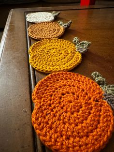 four crocheted coasters sitting on top of a wooden table