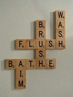 scrabble tiles spelling the word wash, brush, and bathe on a white wall