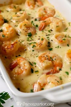 a white casserole dish filled with shrimp and cheese garnished with parsley