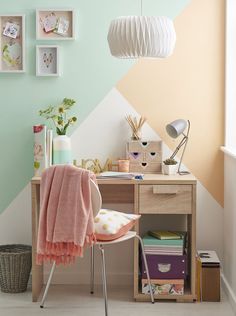 a desk with a chair, lamp and pictures on the wall