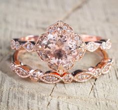 an engagement ring with a pink diamond in the center on top of a piece of wood