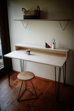 a wooden desk with two shelves above it and a small stool on the other side