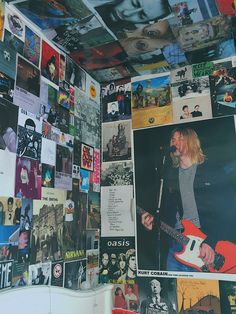 a wall covered in posters and pictures with a man playing an electric guitar on it