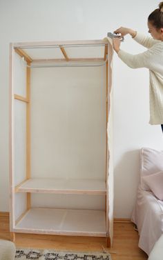 a woman standing on top of a wooden shelf next to a bed