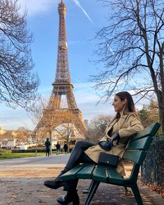 a woman sitting on top of a green bench in front of the eiffel tower