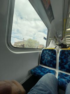 the inside of a train car with blue seats and yellow accents, looking out the window