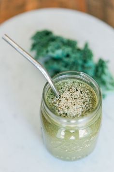 a glass jar filled with green liquid and sprinkles next to broccoli