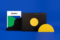 two pieces of paper sitting next to each other on a blue surface with yellow and green shapes