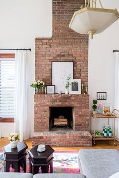 a living room with a brick fireplace and white curtains