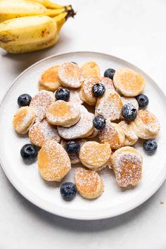 blueberries, bananas and powdered sugar on a white plate next to a banana