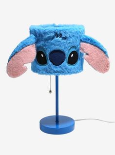 a blue hat with ears and eyes on top of a light stand next to a white background