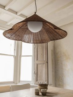 a bamboo lamp hanging from the ceiling over a wooden table with two bowls on it