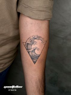 a man's arm with a tattoo on it that has a wave coming out of the ocean