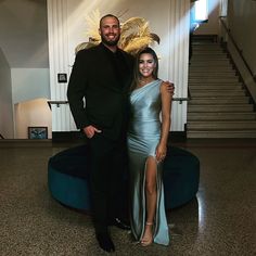 a man and woman standing next to each other in front of a staircase with stairs