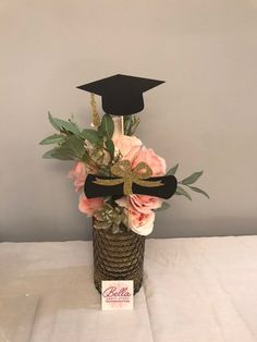 a graduation cap on top of a vase filled with flowers