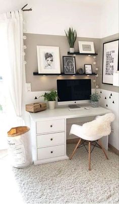 a desk with a computer on top of it in front of a window and some pictures