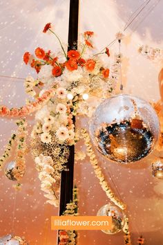 a disco ball hanging from the ceiling next to flowers and other decorations in front of it