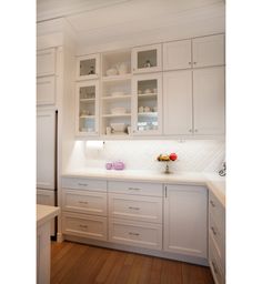 a kitchen with white cabinets and wooden floors