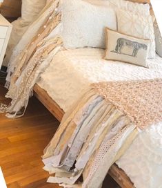 a bed with lots of pillows on top of it next to a night stand and nightstand