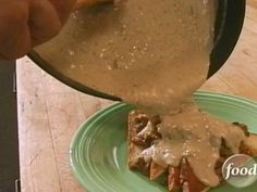 someone is pouring gravy over some food on a green plate