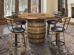 a round wooden table with four stools around it in front of a fireplace and windows