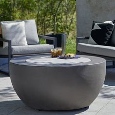 an outdoor table with drinks on it in the middle of a patio area next to two couches