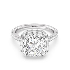 a cushion - cut diamond ring with pave diamonds on the shoulders and sides, set in 18k white gold