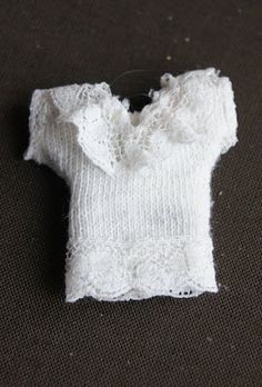 an old white sweater is laying on the floor next to a piece of cloth that has been stitched together