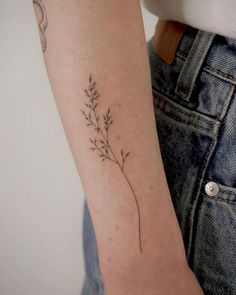 a woman's arm with a small flower tattoo on the left side of her arm